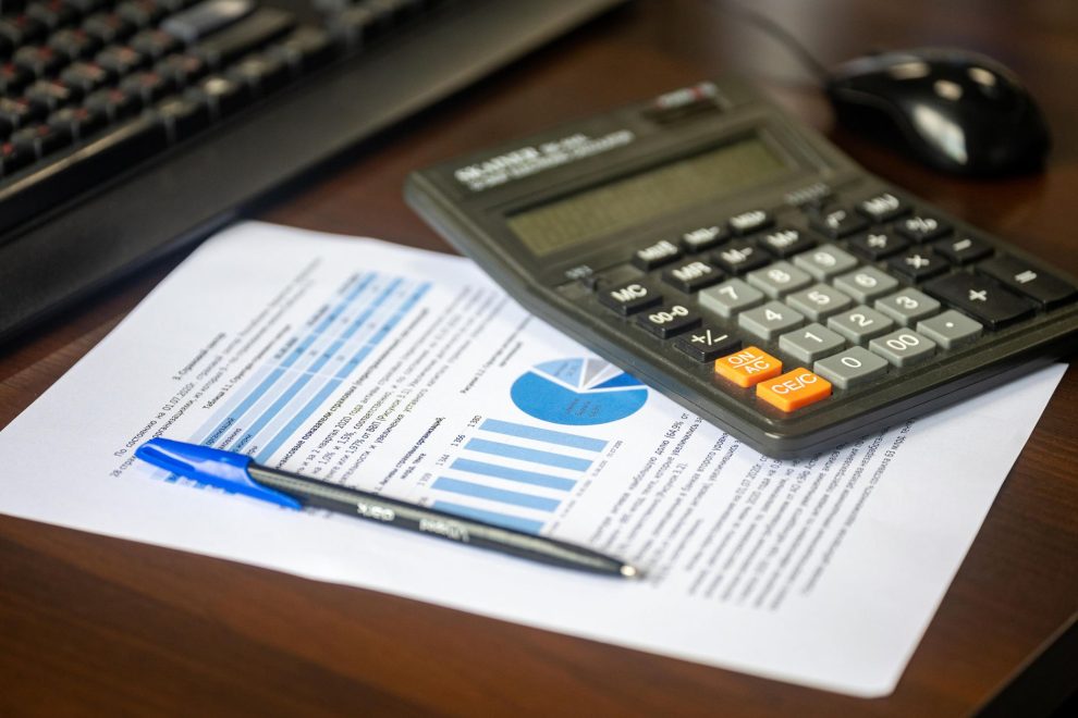 Calculadora, relatório financeiro e caneta sobre uma mesa, representando análise e controle orçamentário.