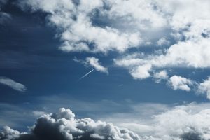 Céu amplo com formações de nuvens e trilhas de condensação deixadas por aviões.