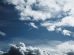 Céu amplo com formações de nuvens e trilhas de condensação deixadas por aviões.