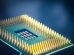 Close-up de um chip de computador com pinos dourados sobre fundo azul.