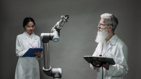 Dois cientistas trabalham com um braço robótico em um laboratório de pesquisa.