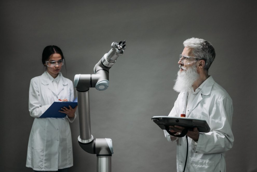 Dois cientistas trabalham com um braço robótico em um laboratório de pesquisa.